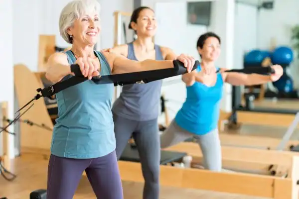 Toning Arms After 60: Empowering Womens Fitness Through Effective Weight Training 2 older woman doing weight training Melksham and resistance in the gym to tone upper arms