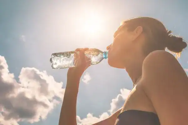 Image of woman drinking water to hydrate Melksham after run.