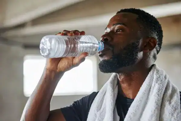 Image of man drinking water to improve hydration Melksham after work out.